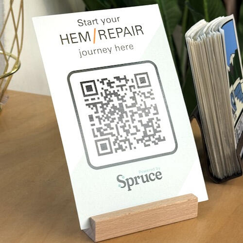 A card on display that shows a QR code and says "start your hem/repair journey here"